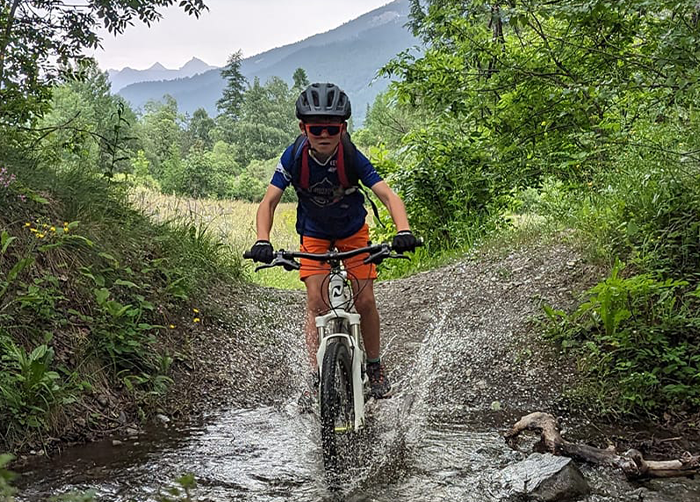 Jeune traversant une rivière en vtt enduro. serre chevalier, briancon